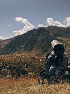 A hiker's backpack rests in a tranquil mountain meadow, perfect for adventure seekers.
