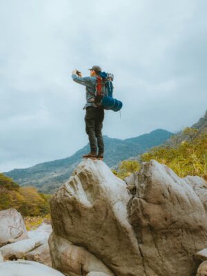 A lone backpacker capturing the stunning mountain landscape from atop a rock.