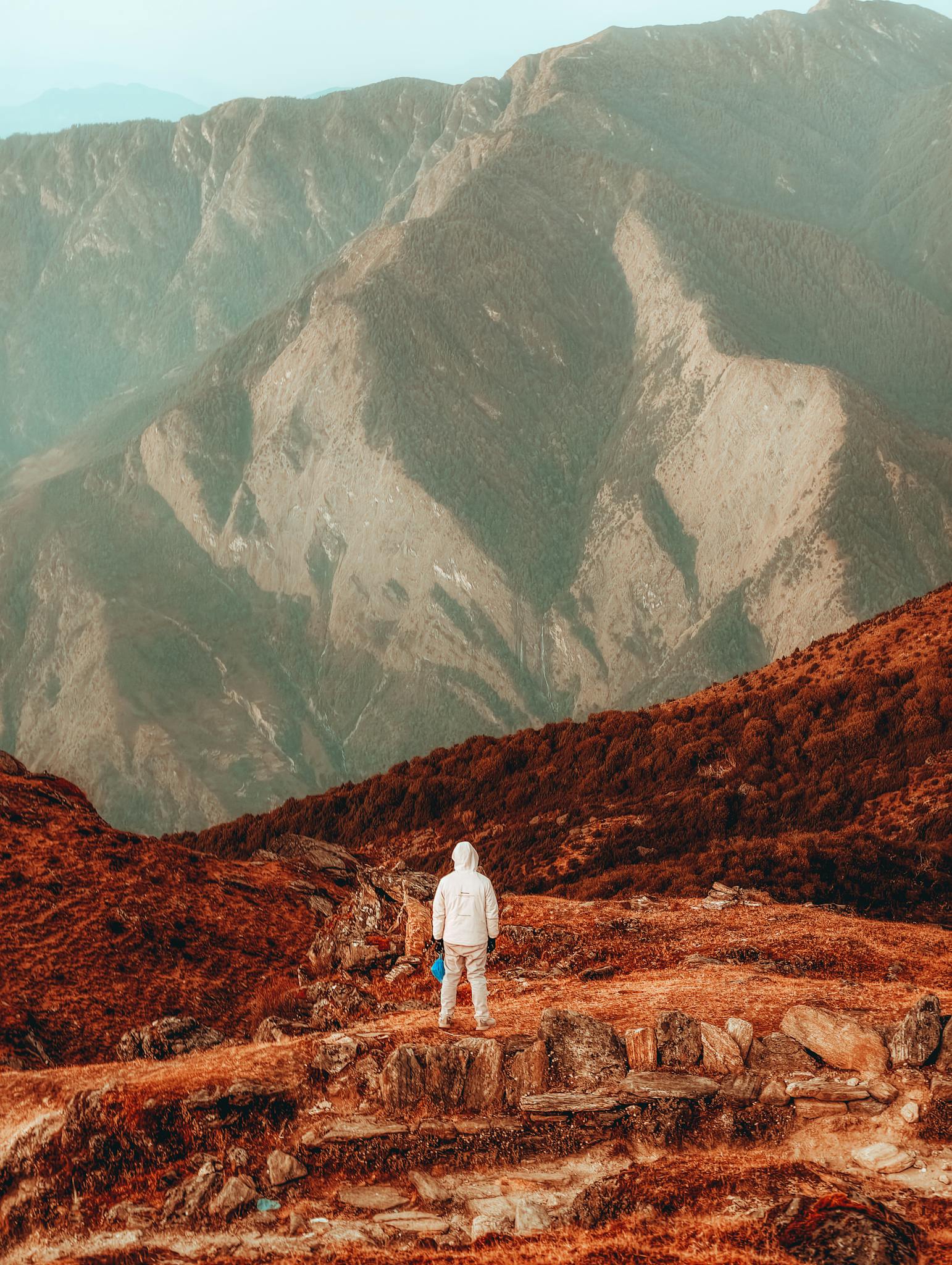 A lone hiker explores the rugged mountain terrain of Nepal with majestic views.