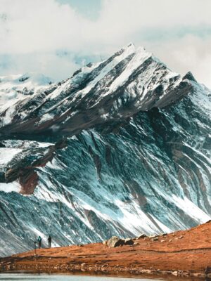 Captivating view of the Himalayas with snowy peaks and hikers by a serene lake in Nepal.