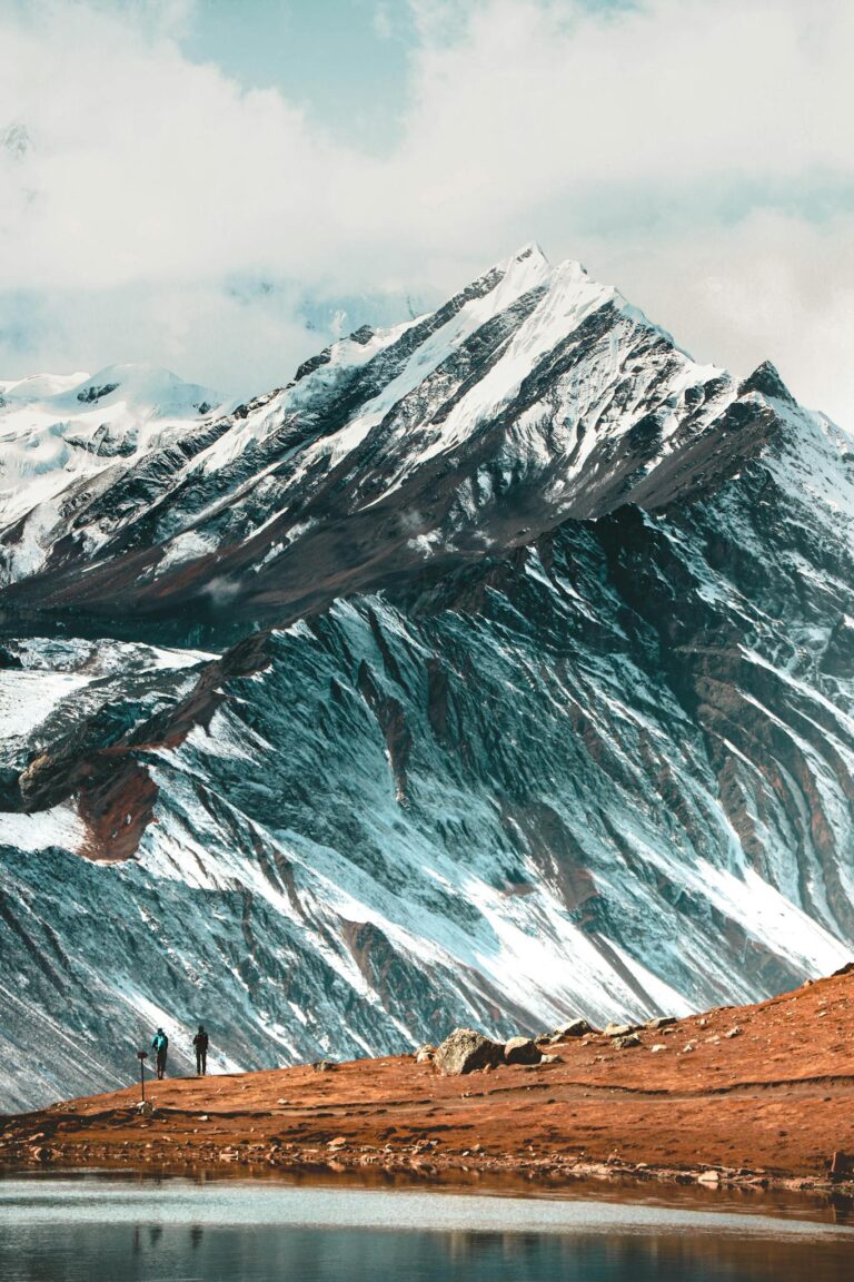 Captivating view of the Himalayas with snowy peaks and hikers by a serene lake in Nepal.