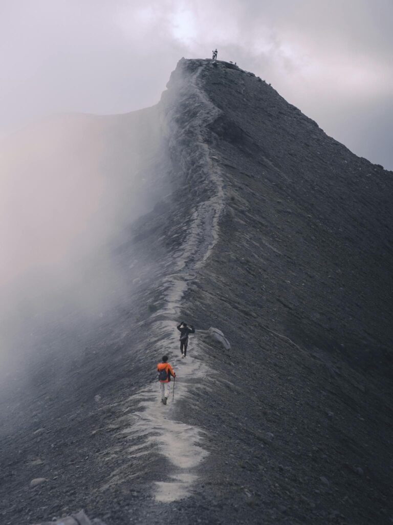 Hikers traverse a dramatic mist-covered mountain ridge, capturing the essence of adventure.